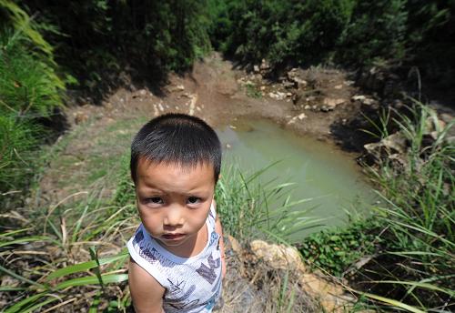 8月7日,重慶綦江區(qū)打通鎮(zhèn)天星村5歲的小朋友牟永站在已經(jīng)見底的水塘旁。該水塘是200多戶村民的飲用水源,現(xiàn)已見底無法取用。新華社記者 李健 攝