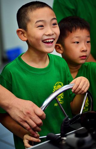 8月7日,在天津海運職業(yè)學院的仿真航海模擬器訓練中心,學生們在教師的指導下體驗船舶駕駛艙模擬環(huán)境。 當日,2013年“少年派的職業(yè)技能體驗之旅”夏令營開營,30名參加夏令營的天津中小學生將在天津海河教育園區(qū)的職業(yè)院校校園參觀現(xiàn)代圖書館、生產(chǎn)實訓場地、3D打印機等,并體驗消防公安工作、學習安全保護知識,了解職業(yè)教育。 新華社發(fā)(游思行 攝)