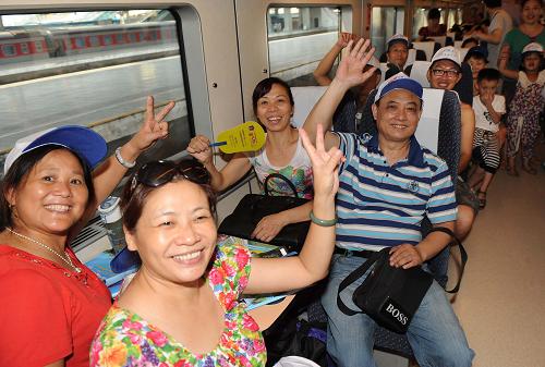 8月9日,乘坐首趟旅游動(dòng)車專列的旅客在車上揮手。新華社記者 李健 攝