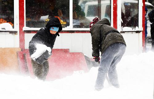 11月18日,一對母子在自家商鋪門前清掃積雪。(新華社記者 王凱 攝)