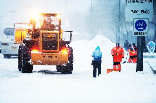 11月18日,清雪車輛和環(huán)衛(wèi)工人在哈爾濱市一條主干道上清掃積雪。(新華社記者 王凱 攝)