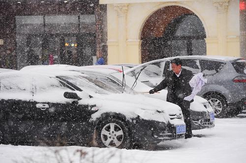 11月19日,長春市民在出行前清理覆滿車身的積雪。(新華社記者 許暢 攝)