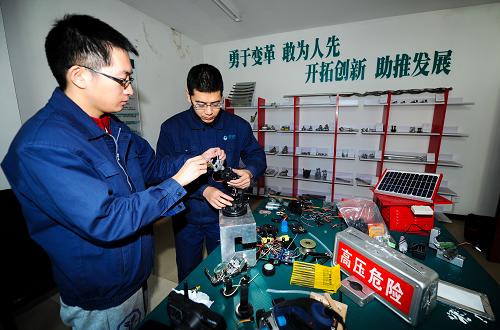 11月21日,張益霖(左)與勞模創(chuàng)新工作室的成員在研發(fā)供電線路清障機(jī)械臂。新華社記者 許暢 攝