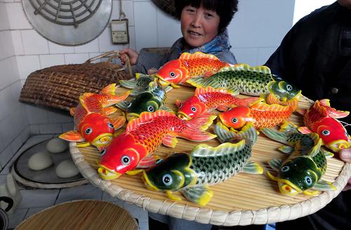 1月15日,山東省萊州市朱橋鎮(zhèn)賈家村村民孫雪堂展示她制作的魚形花餑餑,這種花餑餑蘊(yùn)含“年年有余”的含義。新華社記者 徐速繪 攝