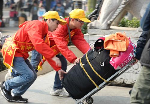 1月16日,志愿者在廣西南寧火車(chē)站幫乘客推行李。新華社記者 周華 攝