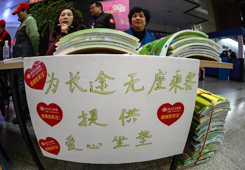 1月16日,志愿者在浙江杭州火車(chē)站候車(chē)廳內(nèi)設(shè)立服務(wù)臺(tái),為長(zhǎng)途無(wú)座乘客提供愛(ài)心坐墊。新華社記者 韓傳號(hào) 攝
