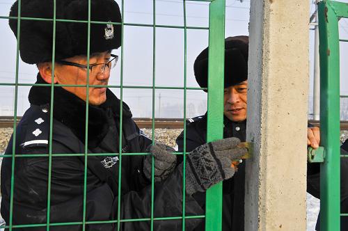 烏魯木齊鐵路公安處西站派出所民警薛勇(左)和郝昕剛將一處鐵軌隔離網(wǎng)松動的螺絲擰緊(1月16日攝)。新華社記者 趙戈 攝