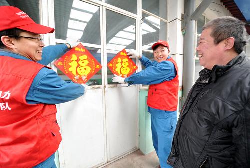 2月13日,供電公司黨員服務(wù)隊(duì)隊(duì)員幫助群眾粘貼印有“福”字的安全用電宣傳品。新華社記者 李曉果 攝