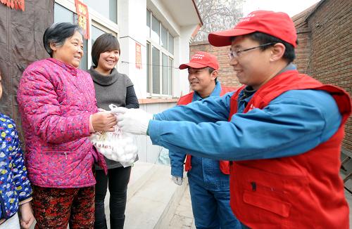 2月13日,共產(chǎn)黨員服務(wù)隊(duì)隊(duì)員(右一)將元宵送到農(nóng)戶手中。新華社記者 李曉果 攝