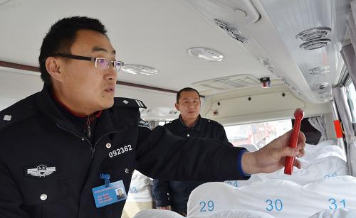 2月17日,在山東濱州京華機(jī)動(dòng)車檢測(cè)站,濱州市交警支隊(duì)車管所駐站民警李執(zhí)勇(左)查看校車破窗逃生錘配備情況。新華社發(fā)(李榮新 攝)