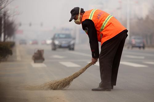 2月21日,一名環(huán)衛(wèi)工人在霧霾籠罩的山東省日照市街頭忙碌。新華社發(fā)