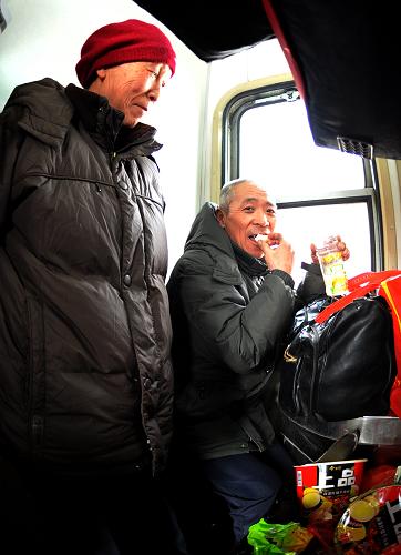 在包頭開(kāi)往南昌的1484次列車上,兩位老人在洗漱間棲身(攝于1月27日)。新華社記者 任軍川 攝
