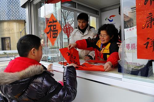 1月29日,志愿者向路人贈送春聯(lián),送上新春的祝福。 當日,世博會后首個城市志愿服務(wù)站亮相上?;春V新飞虡I(yè)街。改造后的服務(wù)站安裝了無框玻璃門窗和空調(diào)、微波爐等設(shè)備,保障志愿者更好地為市民及游客服務(wù),并設(shè)置了紅十字會募捐箱、電信自助查詢一體機等設(shè)施,拓展城市志愿服務(wù)的內(nèi)容。世博會結(jié)束后,上海盧灣區(qū)決定保留5個城市志愿服務(wù)站,用于開展常態(tài)化的志愿服務(wù)。新華社發(fā)(郭長耀 攝)