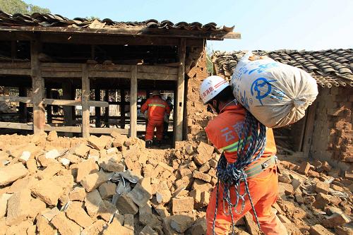 3月11日,在盈江縣平原鎮(zhèn)勐町村拉勐寨,消防官兵幫助群眾從廢墟中搶救糧食。新華社發(fā)(何海燕 攝)