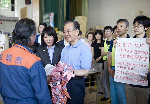 溫家寶在日本名取市災(zāi)區(qū)慰問受災(zāi)民眾 5月21日,中國國務(wù)院總理溫家寶在日本名取市館腰小學(xué)體育館災(zāi)民避難所慰問受災(zāi)民眾。這是溫家寶向名取市市長佐佐木贈送中國汶川地震災(zāi)區(qū)的小朋友折的千紙鶴。 新華社記者黃敬文攝