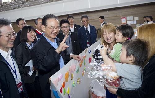 5月21日,中國國務(wù)院總理溫家寶在日本福島吾妻綜合運動公園體育館避難所慰問災(zāi)民。這是溫家寶與避難所內(nèi)的孩子親切交流。新華社記者 黃敬文 攝
