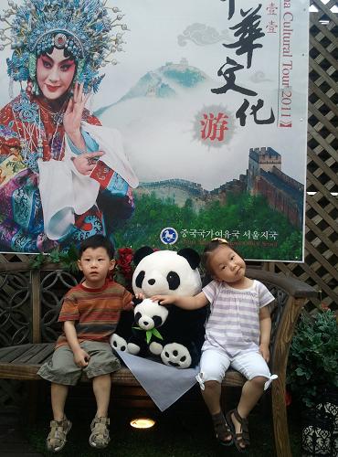 6月18日,兩名韓國小朋友在韓國首爾舉行的“中國文化旅游宣傳月”活動中與大熊貓玩偶合影留念。新華社記者 姬新龍 攝