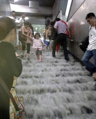 6月23日,在北京地鐵4號(hào)線陶然亭站內(nèi),人們?cè)诒挥晁疀_刷的臺(tái)階上行走。當(dāng)日下午,北京遭遇強(qiáng)雷雨天氣,白晝?nèi)缫梗o行人出行帶來(lái)不便。新華社發(fā)