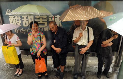6月23日,行人在廣告欄下避雨。當(dāng)日下午,北京遭遇強(qiáng)雷雨天氣,白晝?nèi)缫?,給行人出行帶來(lái)不便。新華社記者 李文 攝