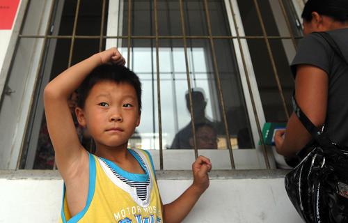 7月12日,在合肥朝霞小學(xué)報(bào)名點(diǎn),一名兒童跟隨母親來(lái)辦理入學(xué)手續(xù)。新華社記者 劉軍喜 攝