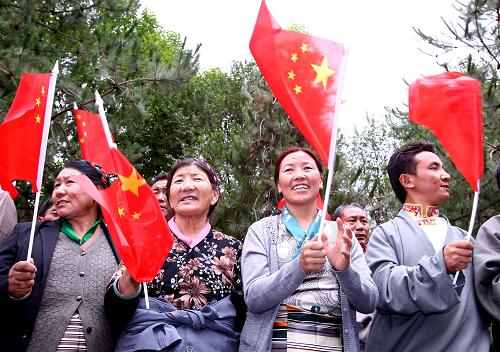 7月17日,身著民族服裝的藏族群眾在拉薩賓館前揮舞國旗,歡迎參加西藏和平解放60周年慶祝活動(dòng)的中央代表團(tuán)抵達(dá)拉薩。 新華社記者陳建力攝