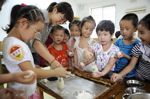 9月9日,浙江省東陽(yáng)市婦聯(lián)幼兒園的老師在指導(dǎo)小朋友做月餅。 新華社發(fā)(包康軒 攝)