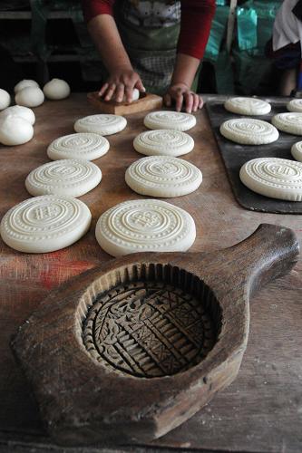 9月10日,在山西運城市新絳縣澤掌村一家蒸饃店,一名村民在用木質(zhì)傳統(tǒng)月餅?zāi)>咧谱髅媸吃嘛?。新華社發(fā)(高新生 攝)