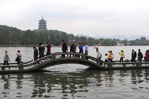 10月1日,游客在西湖長橋上游覽風(fēng)景,后面是雷峰塔。新華社記者 徐昱 攝