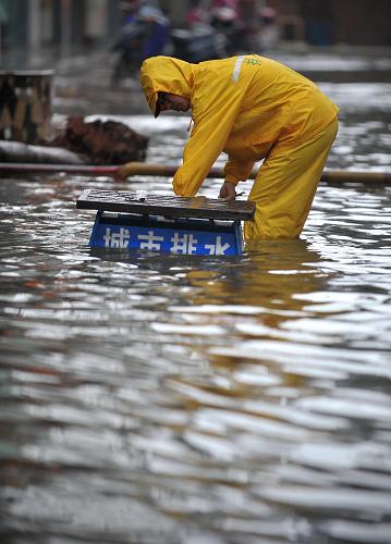 10月5日,??谑姓ぷ魅藛T在清理城市排水管道。強熱帶風暴“尼格”正逐漸遠去,但海南暴雨仍在持續(xù)。受暴雨和海水倒灌影響,海口市多個路段積水嚴重,市內交通和市民生活受到嚴重影響。新華社記者 郭程 攝