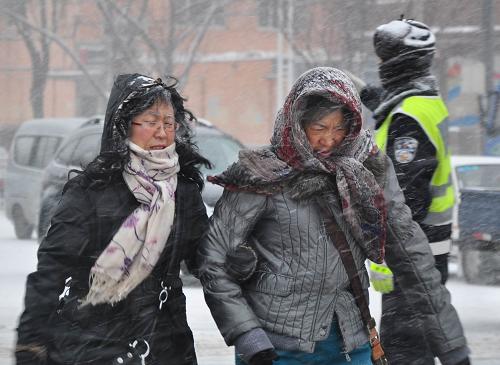 11月23日,牡丹江市街頭,市民冒著紛飛的雪花出行。新華社發(fā)(張春祥 攝)