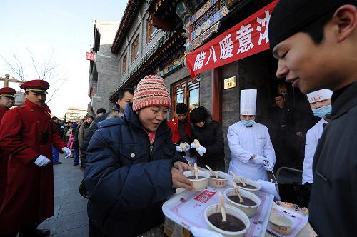 1月1日,北京全聚德前門老店的員工穿著傳統(tǒng)中式服裝在前門步行街向市民游客送臘八粥。當日,2012年的新年與農(nóng)歷臘八節(jié)“喜相逢”。全國各地佛教寺院、藥堂和一些飯店、社區(qū)免費向群眾發(fā)放臘八粥。新華社記者 張旭 攝