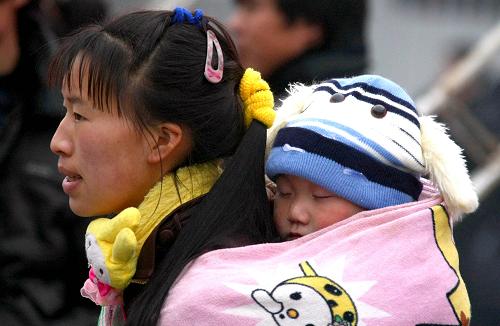 1月8日,在成都火車站,一位小朋友在媽媽背上等待進站乘車。新華社發(fā)(薛玉斌攝)