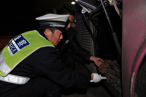 1月24日,在貴州開(kāi)陽(yáng)縣,交警檢查出城車(chē)輛的防滑措施。新華社記者歐東衢攝