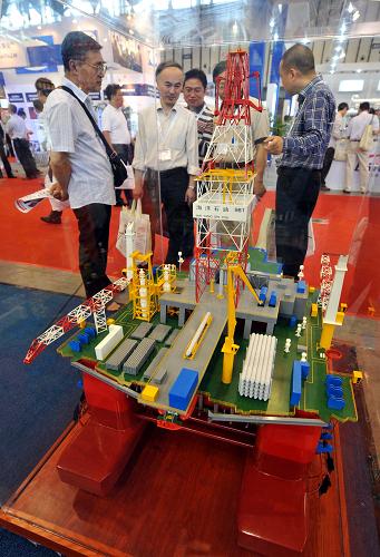 5月23日,業(yè)內(nèi)人士在一參展企業(yè)的海洋石油鉆井平臺(tái)模型前參觀。新華社記者 孫參 攝