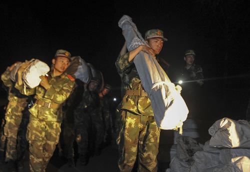 7月1日凌晨,武警官兵向災區(qū)搶運救援物資。新華社記者 江文耀 攝