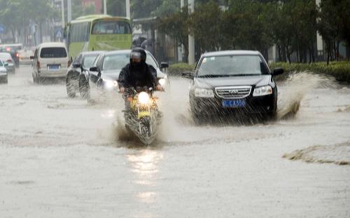 7月14日,江蘇鎮(zhèn)江遭暴雨襲擊,車輛在積水路段行駛。新華社發(fā)(封疆江 攝)