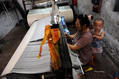 回龍壩一家織布廠內(nèi)一名工人帶著小孩在上班(8月2日攝)。新華社記者 李健 攝
