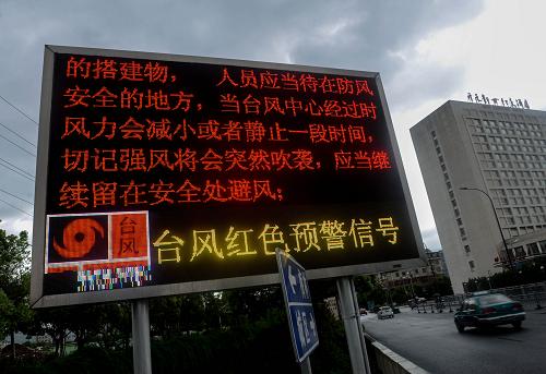 8月7日,車輛從寧波寧??h街頭的臺風(fēng)紅色預(yù)警信號提示屏前經(jīng)過。新華社記者韓傳號攝