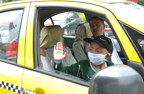 8月7日,患兒高俊杰在出租車上向醫(yī)院送行的醫(yī)護人員揮手告別。新華社記者 劉潺攝