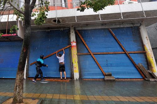 8月7日,遭遇特大暴雨襲擊的浙江象山石浦鎮(zhèn)群眾用木板固定門簾。新華社記者 黃宗治攝