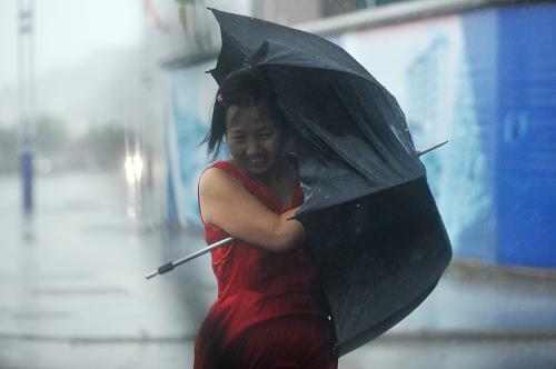 8月7日,行人在遭遇特大暴雨襲擊的浙江象山石浦鎮(zhèn)路上艱難行走。新華社記者 黃宗治攝