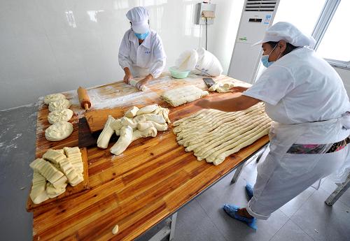 8月24日,南京老字號(hào)“小蘇州”食品公司月餅生產(chǎn)車(chē)間的員工在衛(wèi)生潔凈的臺(tái)面上搟皮。新華社記者 孫參 攝
