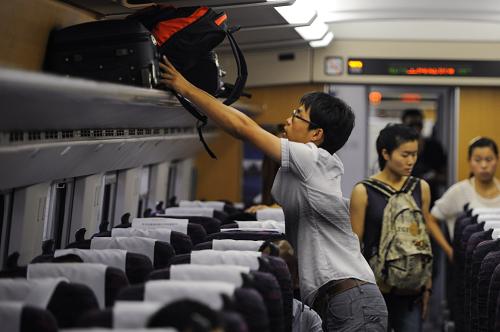 8月26日,一位旅客在去往上海的動車上擺放行李。新華社記者 杜宇 攝