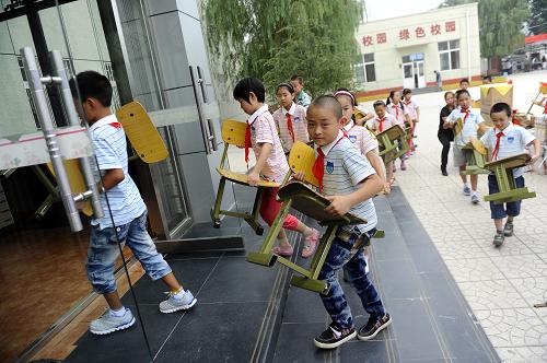 9月1日,在北京市房山區(qū)河北鎮(zhèn)中心小學(xué),學(xué)生們?cè)陂_學(xué)典禮結(jié)束后將凳子搬回教室。新華社記者 金良快 攝