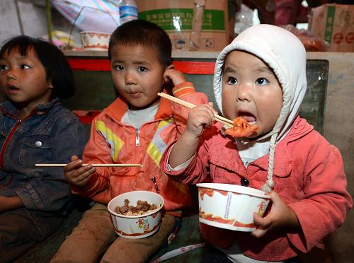 9月16日,地震重災(zāi)區(qū)的幾名兒童在安置點(diǎn)吃飯。近日,云南省彝良縣地震重災(zāi)區(qū)羅澤河鎮(zhèn)在山溝安置點(diǎn)建起了簡(jiǎn)易的愛心大食堂,每天為1000多名受災(zāi)群眾和救援人員免費(fèi)供應(yīng)熱氣騰騰的飯菜。新華社記者 楊宗友 攝