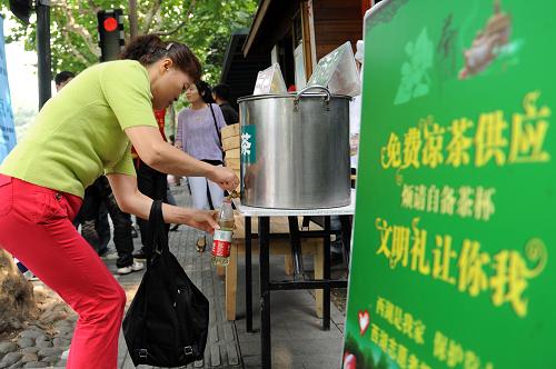 10月5日,游客在西湖景區(qū)蘇堤入口處的微笑亭自取涼茶。新華社記者 黃宗治 攝