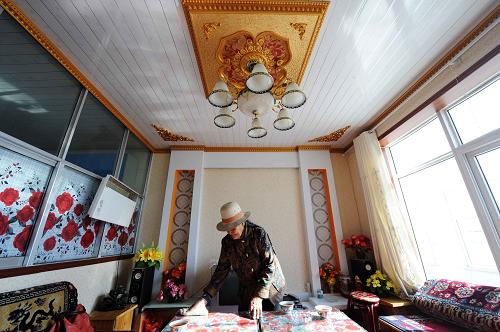 11月16日,在新牧區(qū)示范點,73歲的同寶村藏族老人格巴在自家客廳里整理。新華社記者 侯德強 攝