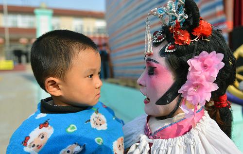 “莊戶劇團(tuán)”樂鄉(xiāng)村 11月24日,村民苗學(xué)燕的兒子有點(diǎn)認(rèn)不出化了裝的媽媽。 農(nóng)忙已過,山東鄒平縣西黃村的“莊戶劇團(tuán)”又開始忙碌起來,十里八鄉(xiāng)的村莊都紛紛邀請她們?nèi)パ莩觥N鼽S村業(yè)余劇團(tuán)1998年正式成立,由村民們自發(fā)、自愿結(jié)合,不計(jì)任何報(bào)酬。十幾年來,業(yè)余劇團(tuán)的演職人員不斷變化,但為村民義務(wù)演出的傳統(tǒng)和對民間戲曲的喜愛一直沒改變。現(xiàn)在,西黃村業(yè)余劇團(tuán)的成員們已經(jīng)整理、編排傳統(tǒng)劇目37出,每年為村民演出40余場次。 據(jù)山東省文化部門統(tǒng)計(jì),山東目前有農(nóng)村民辦劇團(tuán)5200個(gè),這些“莊戶劇團(tuán)”根植鄉(xiāng)村大地,豐富繁榮了農(nóng)村文化生活。 新華社記者 朱崢攝