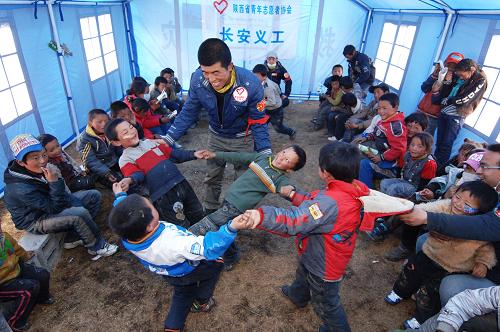 12月5日是第27個(gè)國際志愿者日,因“志”而行,因“愿”而動(dòng),每一位志愿者用自身的點(diǎn)滴行動(dòng),助力公益事業(yè)、為社會(huì)發(fā)展貢獻(xiàn)力量。這些可愛的志愿者就生活在我們身邊,他們利用業(yè)余時(shí)間,不為任何報(bào)酬參與社會(huì)服務(wù),用堅(jiān)持和愛心向社會(huì)傳遞正能量。 圖為2010年4月20日,在位于玉樹公園受災(zāi)群眾安置點(diǎn)的“愛心教室”,一位志愿者在和孩子們做游戲。新華社記者 丁海濤 攝
