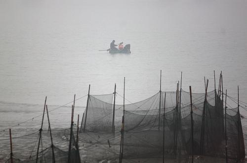 1月13日,漁民在大霧籠罩的長江江蘇南通段江面上捕魚。新華社發(fā)(朱吉鵬 攝)